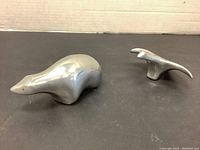 Metal bear and goose figurines from side and angled views showing shapes and size.