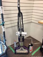 Full view of Bissell CrossWave Pet Pro multi-surface cleaner upright with cleaning supplies including bottles and a mop pad.