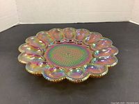 Top-down view of carnival glass deviled egg plate showing iridescent iridescence and hobnail pattern in center and scalloped egg indents