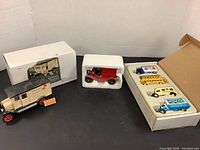 Overall lot view showing the 1924 Chevy truck with box, Fire Chief truck in protective foam, and box of 4 mini trucks on dark tabletop.