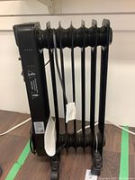 Side view of black oil filled radiator heater showing heating fins and wheels