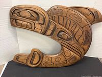 Full front view of Kwakiutl killer whale and raven carving showing overall shape and open circle center