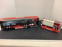 Two Kenworth die cast trucks in original packaging: the W900 Hardcore Chopper (large) and the smaller T3000 model.