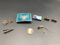 Full lot image showing all jewelry items on black background including the belt buckle, money clip, pendant, cufflinks, and tie pins.