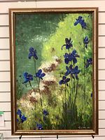 Full view of framed oil painting of blue flowers against green background