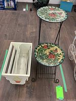 Full view of metal folding plant stand with mosaic round shelves and wooden magazine rack side by side on wood floor.