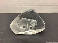 Front view of clear glass sculpture with frosted polar bear inside on a black background.