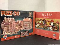 Box front of 3D Puzzle Alsace and Red Hat puzzle showing designs and packaging, both unopened.