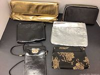 Lot of gold, black, and silver small purses and makeup bags, including floral pattern and black leather items