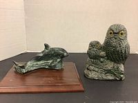 Two composite trophies: a whale mounted on a wooden base to the left and a pair of owls on the right
