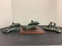 Photo showing two whale sculptures and a pair of seals arranged side by side on a black surface against a white background.