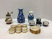 Photo showing both blue and white vases, vintage Italian pepper mill, Japanese sake set, and napkin rings with coasters arranged together