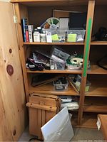 Shelf with organized art supplies including bottles, books, color wheel, and containers of brushes and paints.