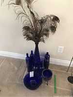 Overall collection of blue glass mixing bowls, various cobalt bottles, large cobalt vase with peacock feathers.