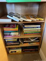 Books arranged on a wooden bookshelf showing variety of titles on sports, strategy, language, and teaching skills.