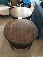 Pair of round wooden end tables positioned side by side showing overall condition and structure.