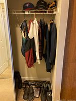 Photo of men's jackets, shirts, hats on wire rack and shoes on floor beneath