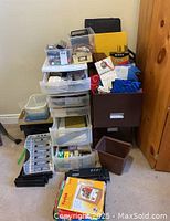 Overall view of plastic storage organizer with several drawers open or closed, metal filing cabinet, and assorted office supplies piled around them.