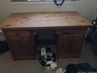 Front view of large pine desk with closed drawers and cabinet doors.