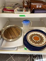 Shelf with aluminum tray, Japanese plate, blue juice jug, and plastic trays.
