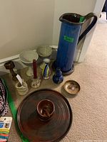 Wide view of lot on carpet showing blue Denby pitcher with handle tagged, multiple candle holders, small pottery items, serving platter and dip bowl.