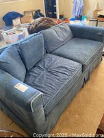 Front view of the blue pullout sofa with slipcover showing cushions and slightly worn fabric.