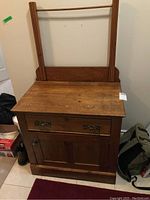 Front view of antique oak wash stand with drawer and cabinet door closed, showing attached mirror frame without mirror.