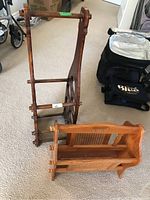 Image shows handcrafted wooden wine bottle rack standing upright, holding no bottles, next to a smaller wooden magazine holder with cane sides.