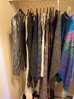 Women's clothing including tops and dresses hung on hangers showing multiple colors and textures.