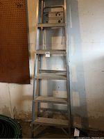 Front view of the 5 step aluminum utility ladder leaning against a wall.