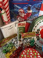 Image showing Christmas laser landscape light with waving Santa, decorative wrapping paper rolls, gift bows, and a round metal Christmas tin