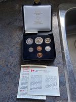 Top view of complete 1977 Canadian coin set in fitted black case with coins in velvet slots and Royal Canadian Mint logo inside lid.