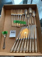 Overview of box showing grouped dinner knives, forks, tablespoons, teaspoons and one mismatched spoon