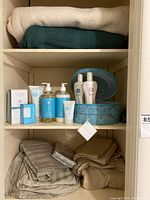Wide view of linen closet with blankets on top shelf, bath products in middle shelf, and folded linens on bottom shelves.