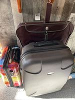 Three luggage pieces together: large hard case, medium colorful hard carry-on, and hanging soft case behind