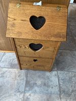 Front view of the oak potato box showing three heart-shaped wire mesh cutouts and hinged top lid.