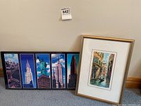 Framed collage of 5 vertical NYC landmark photos including Chrysler Building, Statue of Liberty, and Empire State Building in horizontal arrangement, gold frame on floor.