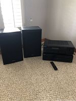 Photo of the Sony stereo receiver and 5-disc CD player stacked on a carpeted floor next to two black speaker boxes. Remote control placed in front.