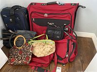 Full view of the set showing the three travel bags and five purses arranged together on a hardwood floor and mattress.