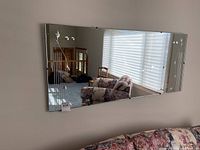 Straight on photo of wall mirror showing whole reflective surface and floral etching in corners.