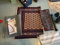 Photo of three rugs laid on the floor showing different patterns and sizes including a folded smaller rug and a larger detailed rug.