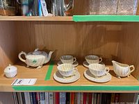 Full set on shelf, showing teapot, cups, saucers, creamer and sugar bowl