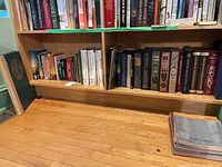 Two wooden shelves filled with assorted books of various sizes and genres.
