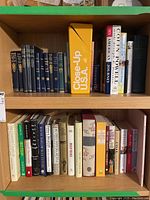 Two wooden shelves filled with various hardcover and paperback books including classical literature