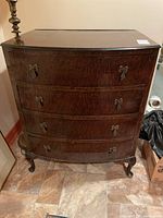 Front view of vintage four drawer dresser showing curved drawer fronts and metal bow handles.