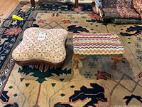 Pair of small footstools side by side on a patterned rug, one with floral upholstery and wooden curved base, the other rectangular with multicolor zigzag fabric upholstery and wooden legs.