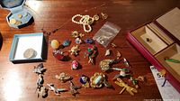 Overview of all jewelry laid out on wood surface showing necklaces, earrings in boxes, multiple brooches