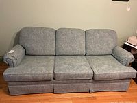 Full front view of the three-seat couch showing the gray patterned fabric and three back cushions.