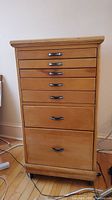 Front view of wooden storage cabinet showing seven drawers and metal handles