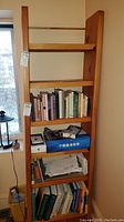 Full view of wooden shelf with books, papers, and a box on shelves